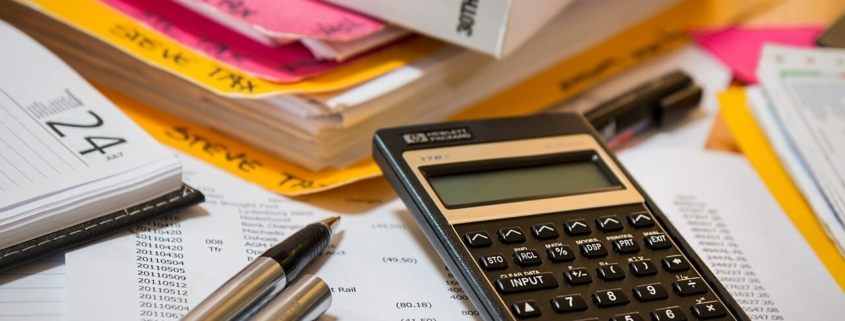 Foto de una calculadora, unos bolis y una carpeta donde guardar todo lo relacionado con el IS